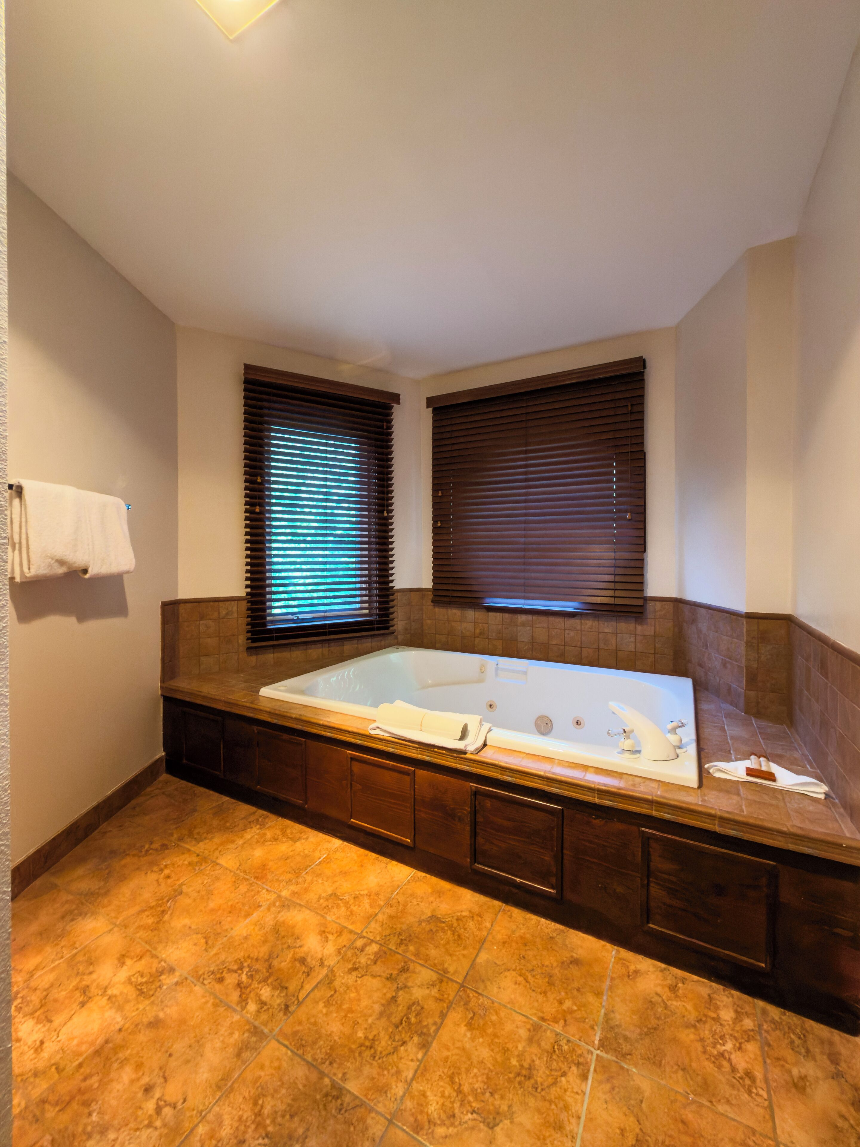 A bathroom with a large bathtub, wooden cabinetry, and a tiled floor.