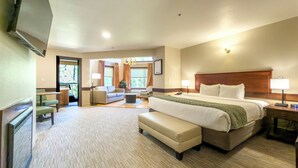 Een hotelkamer met een groot bed, een zithoek met een bank en stoelen, een bijzettafeltje en een televisie.