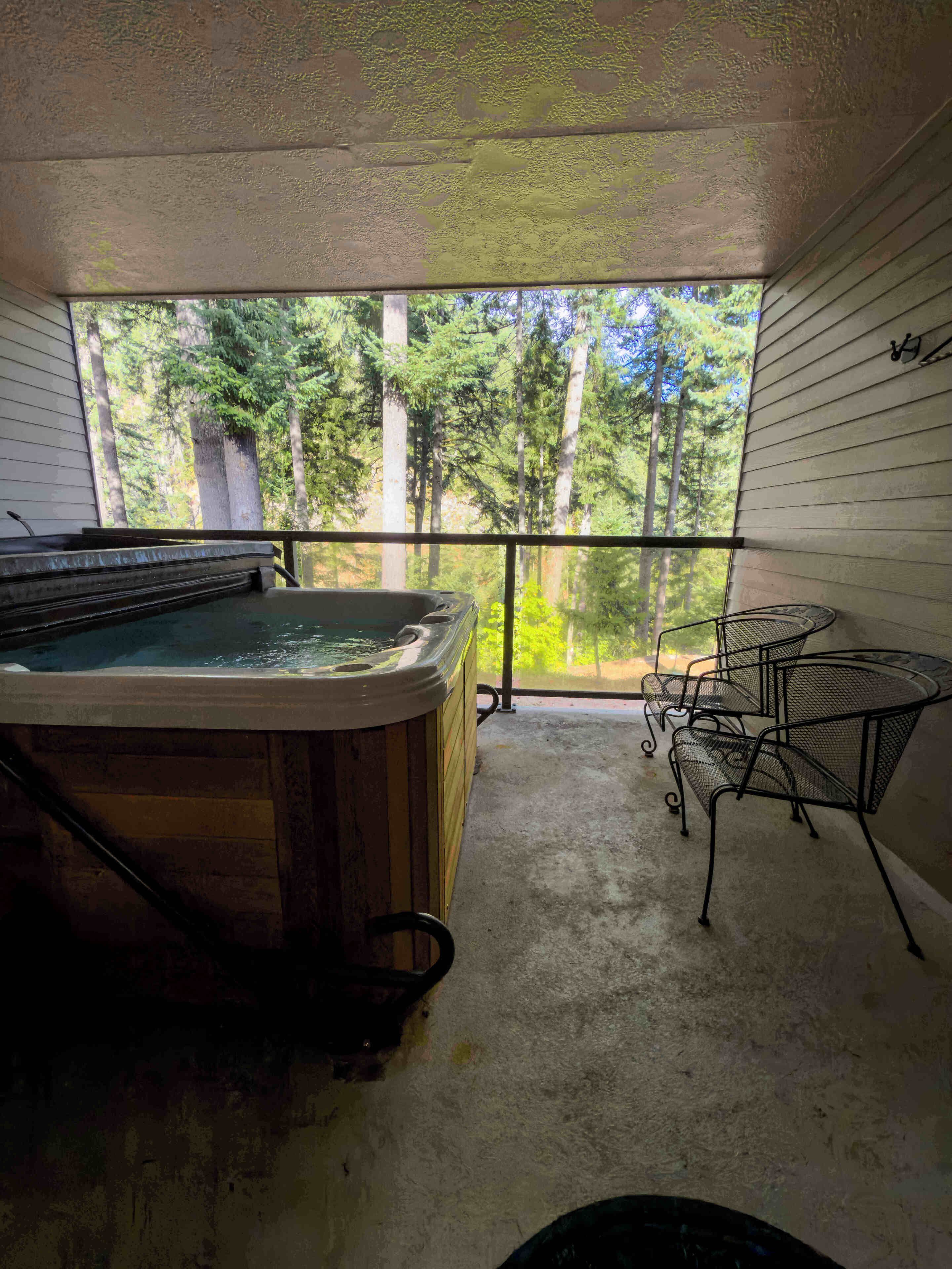 A hot tub on a balcony with a view of a forest.
