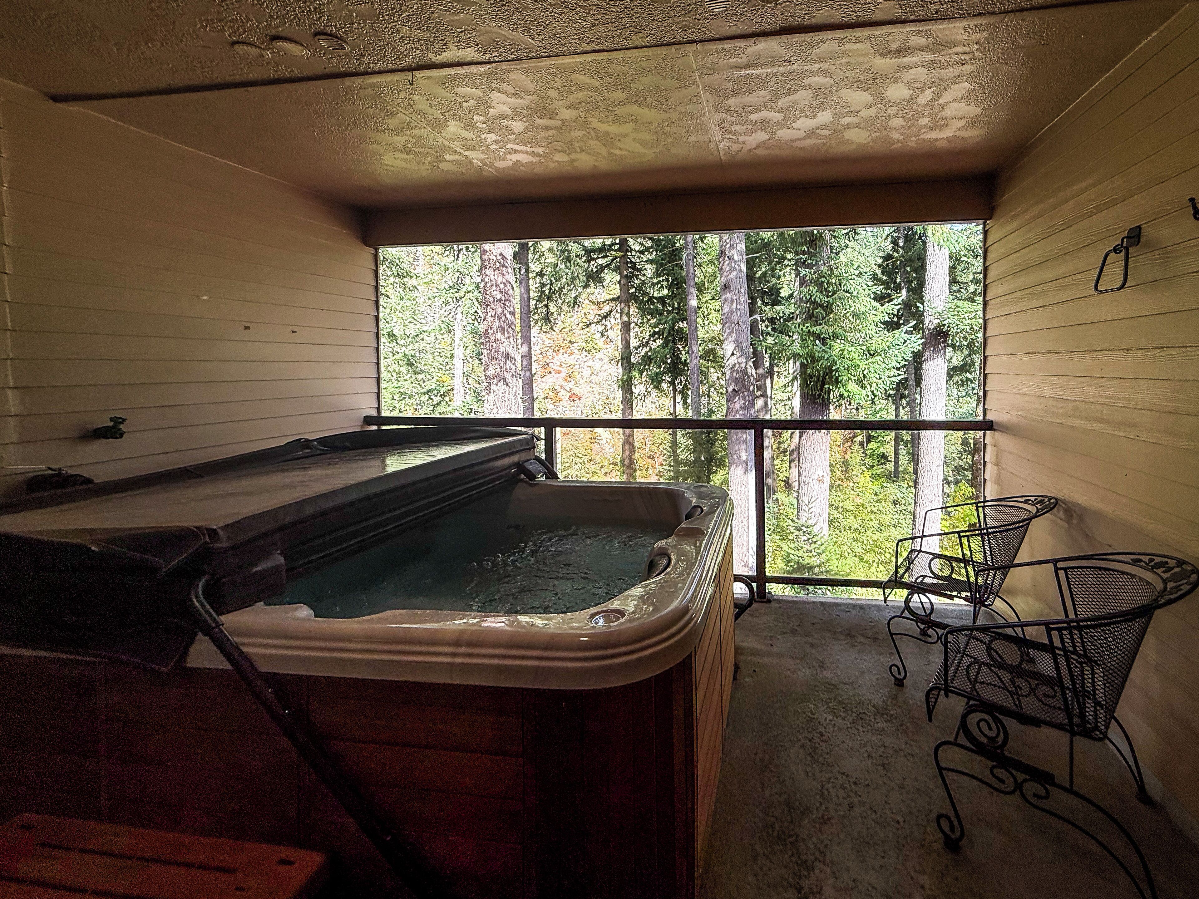 Un jacuzzi en una habitación con vistas a árboles.