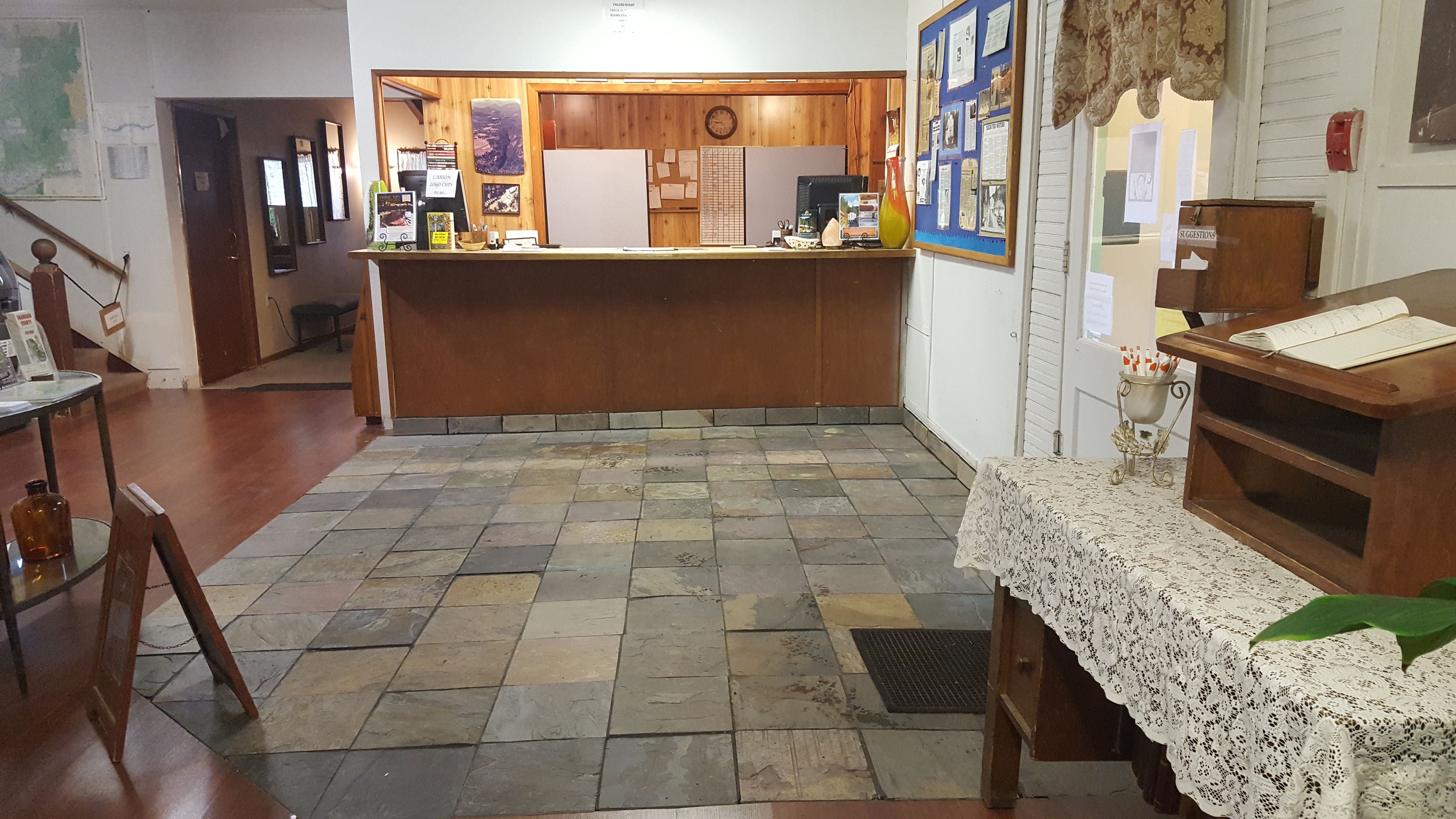 A reception area with a wooden counter, a bulletin board, and a tiled floor.