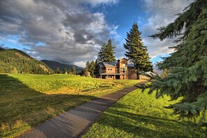 A large, multi-story building with a prominent entrance, surrounded by lush greenery and mountains in the background. - Carson Hot Springs Resort (Carson)