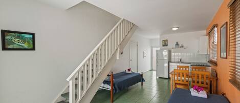 Una stanza con un letto, una sedia di legno, un tavolino e una scala.