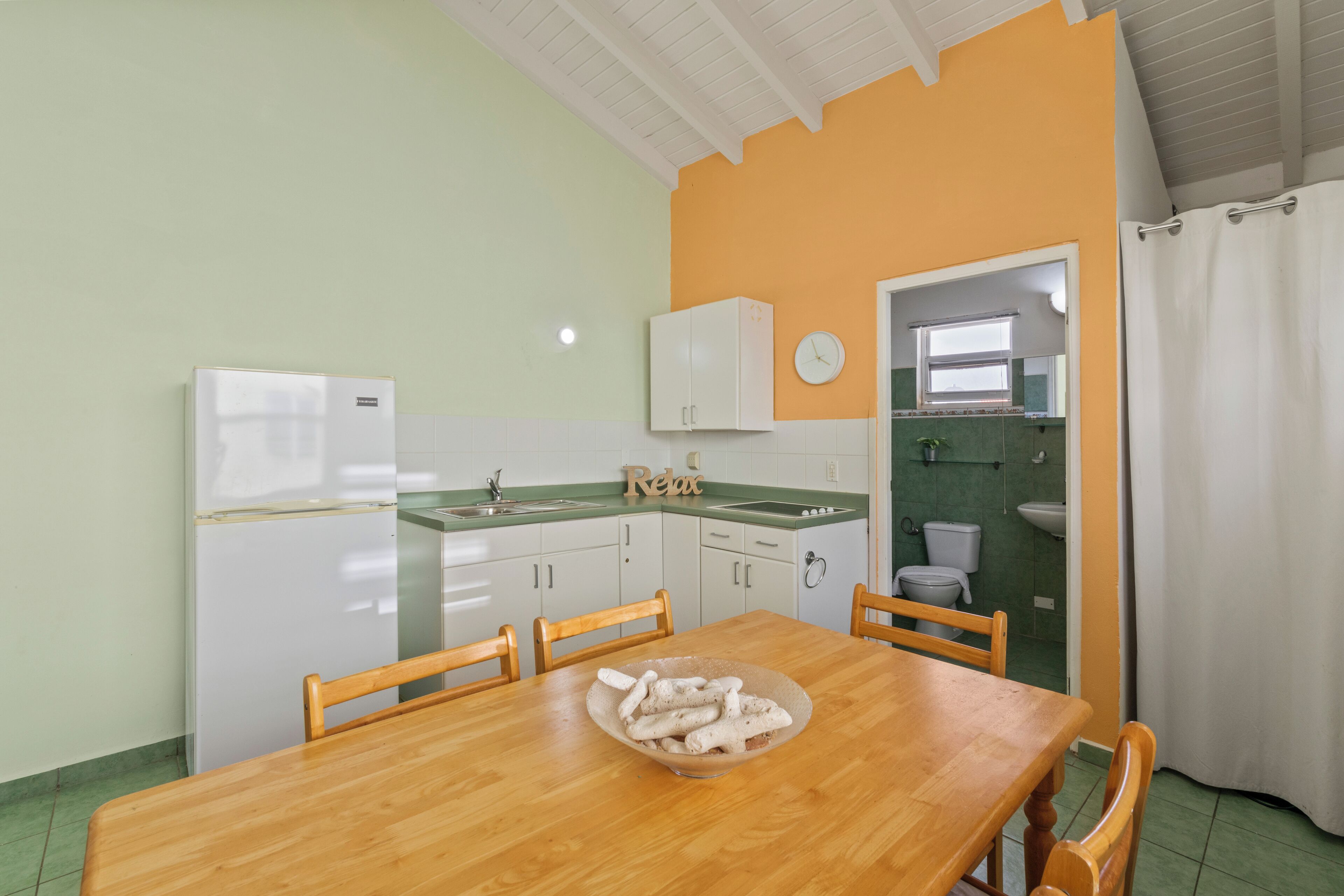 Cocina compacta con zona de comedor, que incluye una mesa de madera, sillas y un bol con palitos de pan.