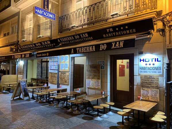 A restaurant named "A Taberna do Xan" with outdoor seating and a sign indicating "HOTIL HABITACIONES" with amenities like WiFi. - Hostal Hotil (A Coruña)