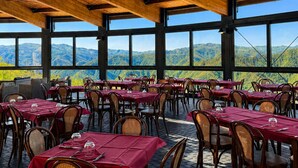 A restaurant with tables set for dining, large windows, and a view of mountains.