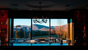A bar with a large window view of mountains and a chandelier. - Hotel Domestique (Travelers Rest)
