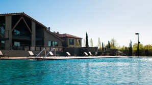 A swimming pool with lounge chairs and a building with balconies. - Hotel Domestique (Travelers Rest)