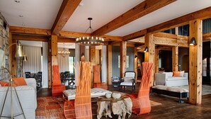 A spacious room with wooden beams, a large chandelier, and a cozy seating area with orange chairs and a white sofa. - Hotel Domestique (Travelers Rest)