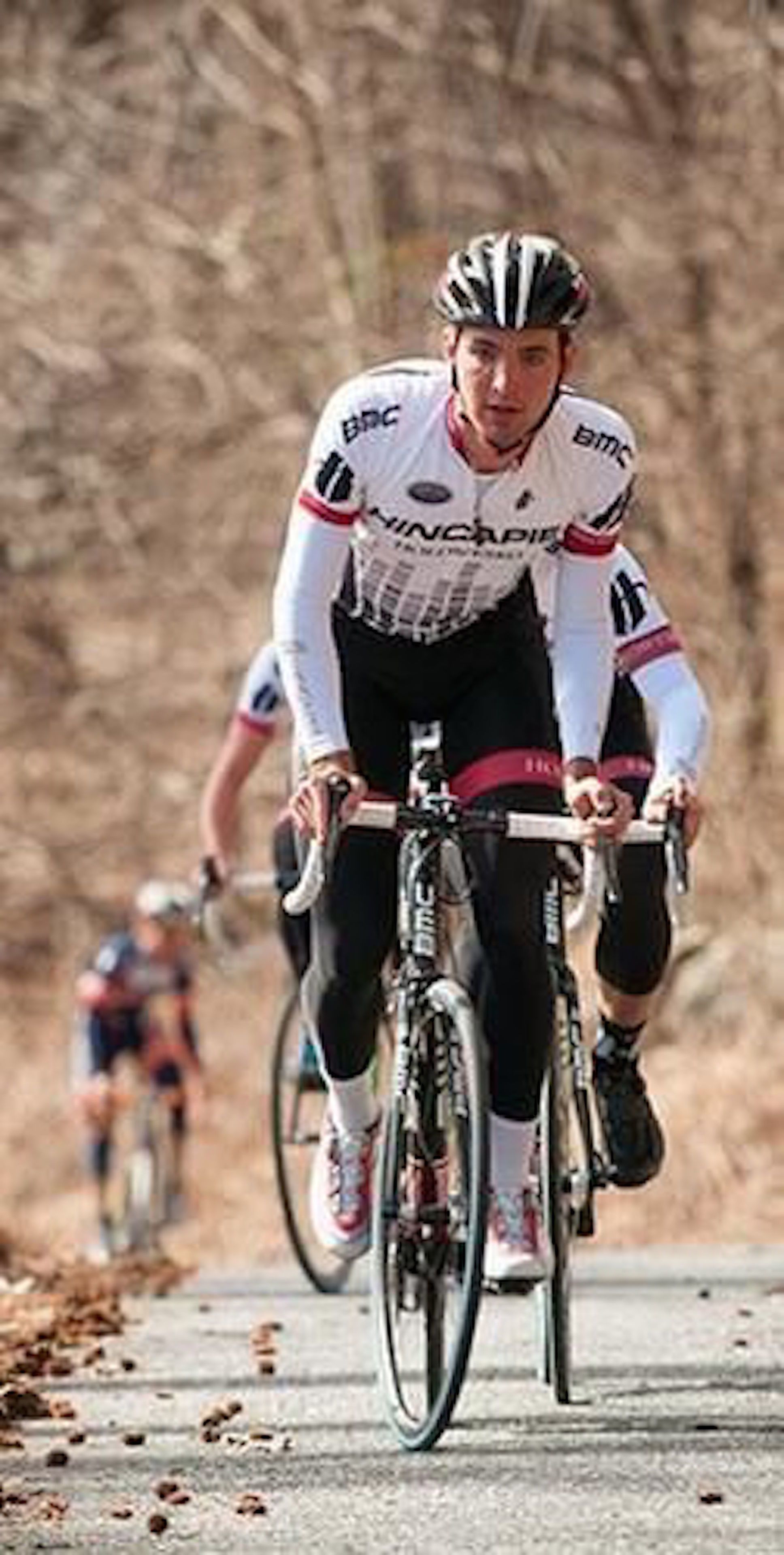 A cyclist in a white and black outfit riding a road bike.