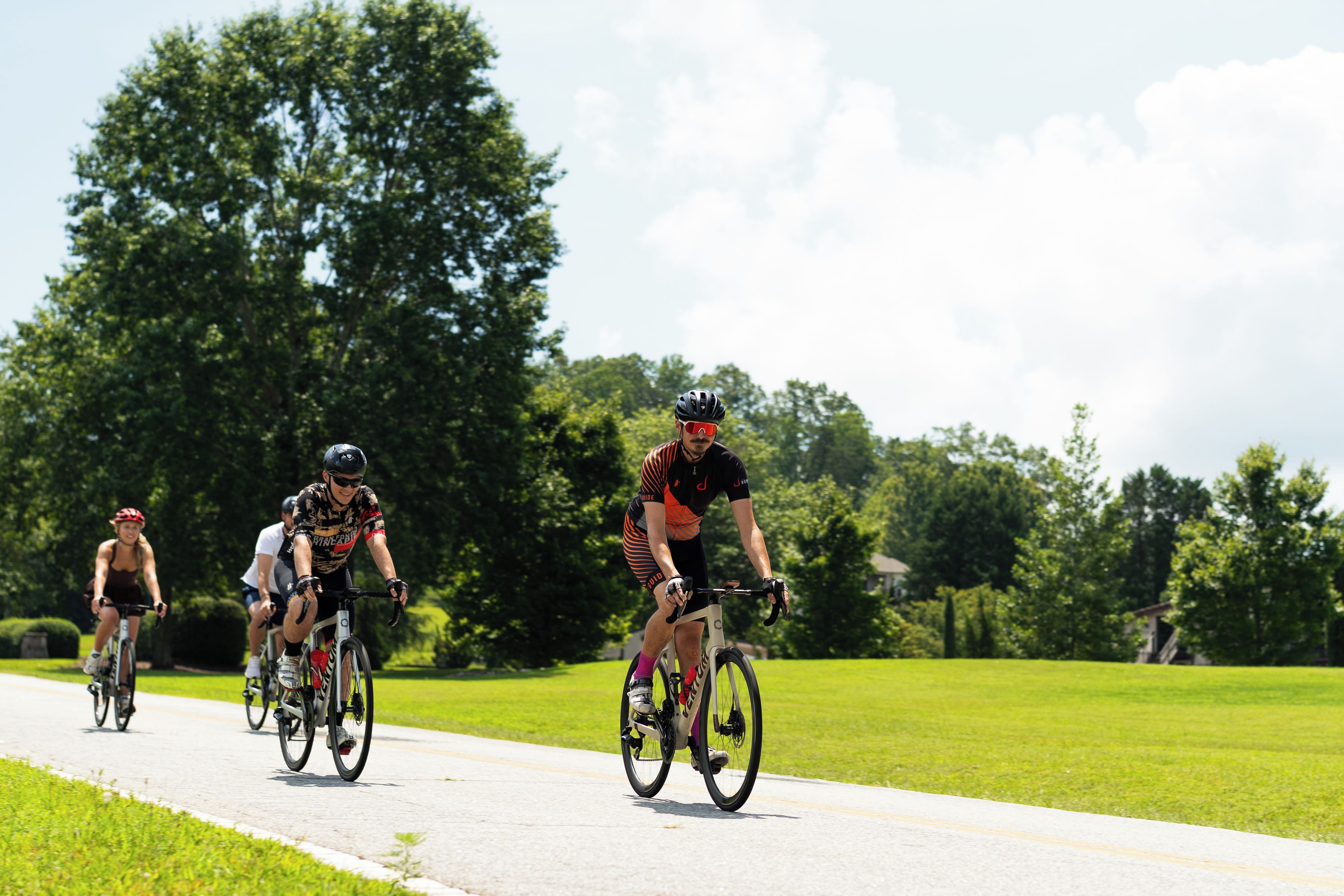 Un groupe de cyclistes sur une piste cyclable, entouré de verdure.