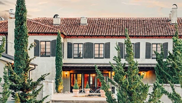A two-story house with a tiled roof, a stone fire pit, and outdoor seating. - Hotel Domestique (Travelers Rest)