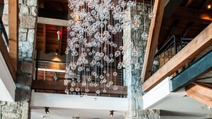 A restaurant with a stone fireplace, hanging crystal chandelier, and multiple dining tables set with white tablecloths and wine glasses. - Hotel Domestique (Travelers Rest)