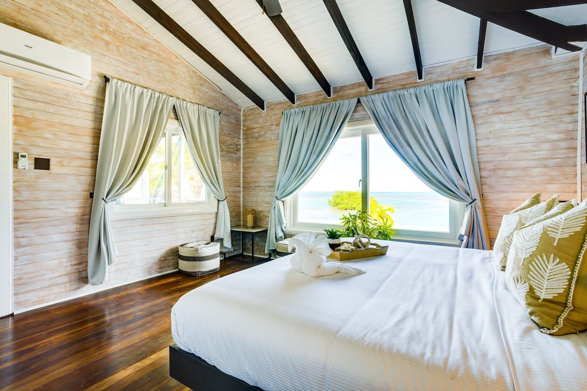 Een slaapkamer met een groot bed, houten wanden en uitzicht op zee.