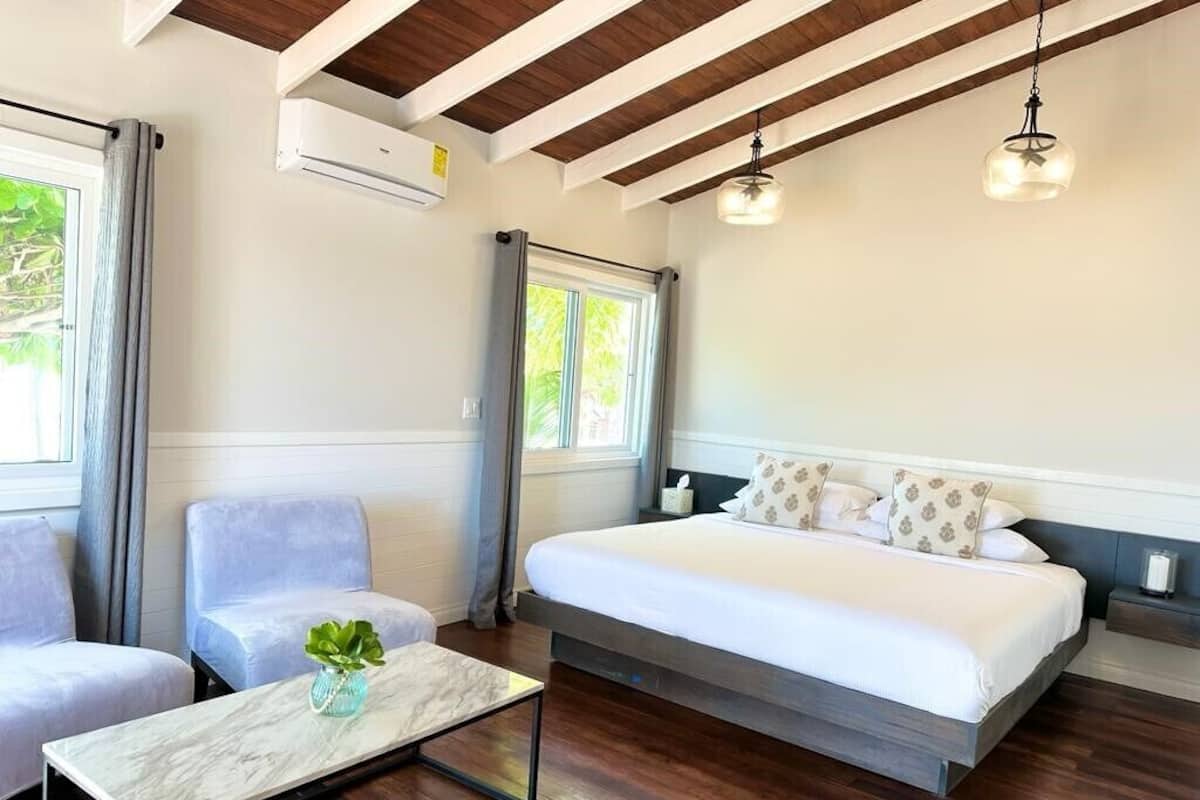 Een slaapkamer met een groot bed, een zithoek met een tafel en een raam met gordijnen.