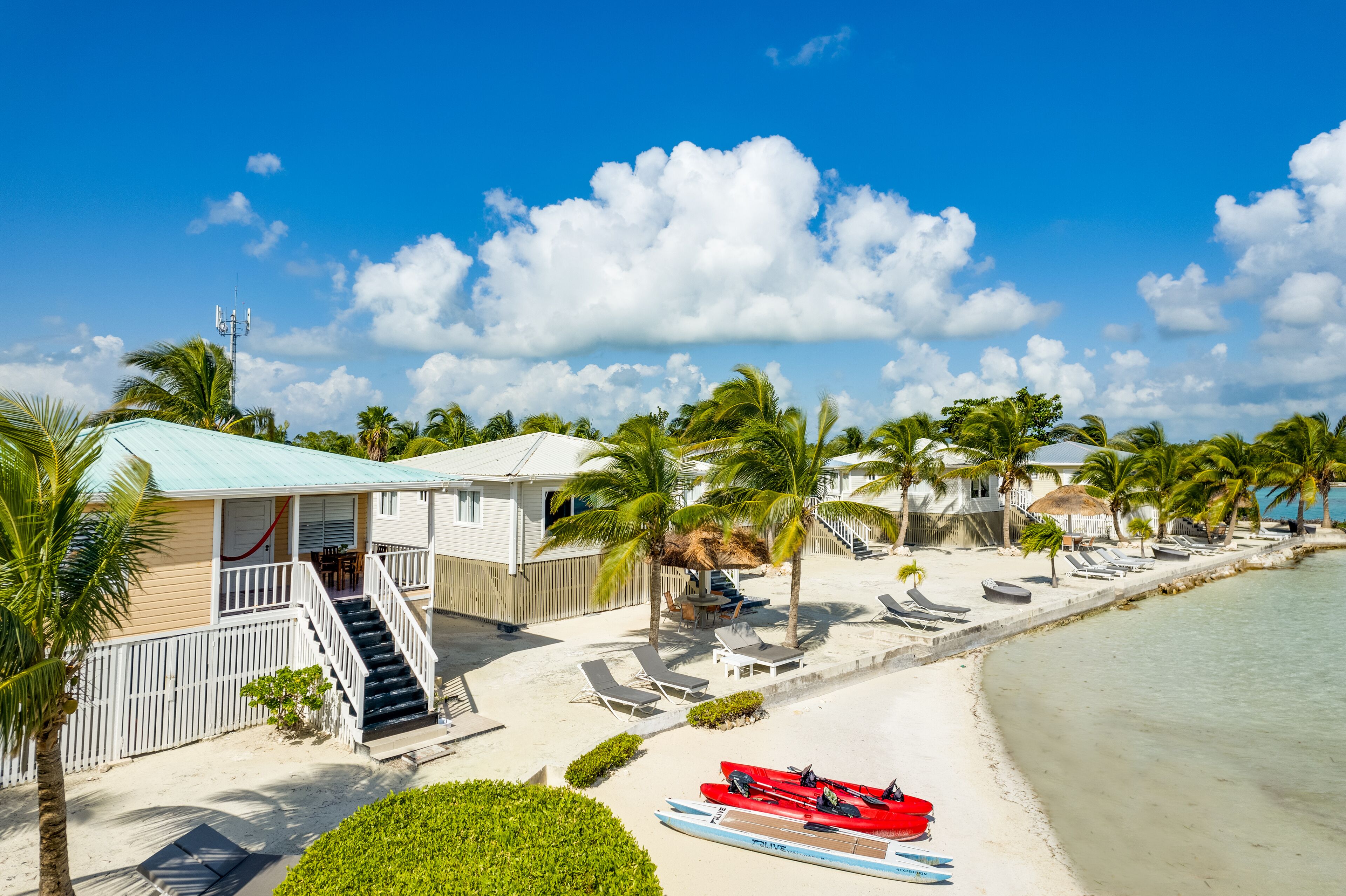 A beachfront property with a swimming pool, beach chairs, and a red boat.