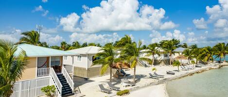 A beachfront property with a swimming pool, beach chairs, and a red boat.