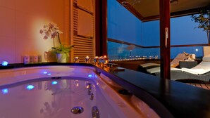 A spa area with a hot tub, candles, and a view of the city at dusk. - Maistra Select All Suite Island Hotel Istra  (Rovinj)