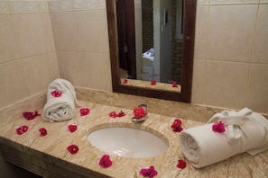 A bathroom with a marble sink, a mirror, and a towel. - Pousada Imperio do Sol (Tibau do Sul)