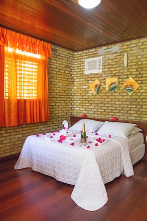 A room with a bed, a window with orange curtains, a brick wall, and artwork. - Pousada Imperio do Sol (Tibau do Sul)