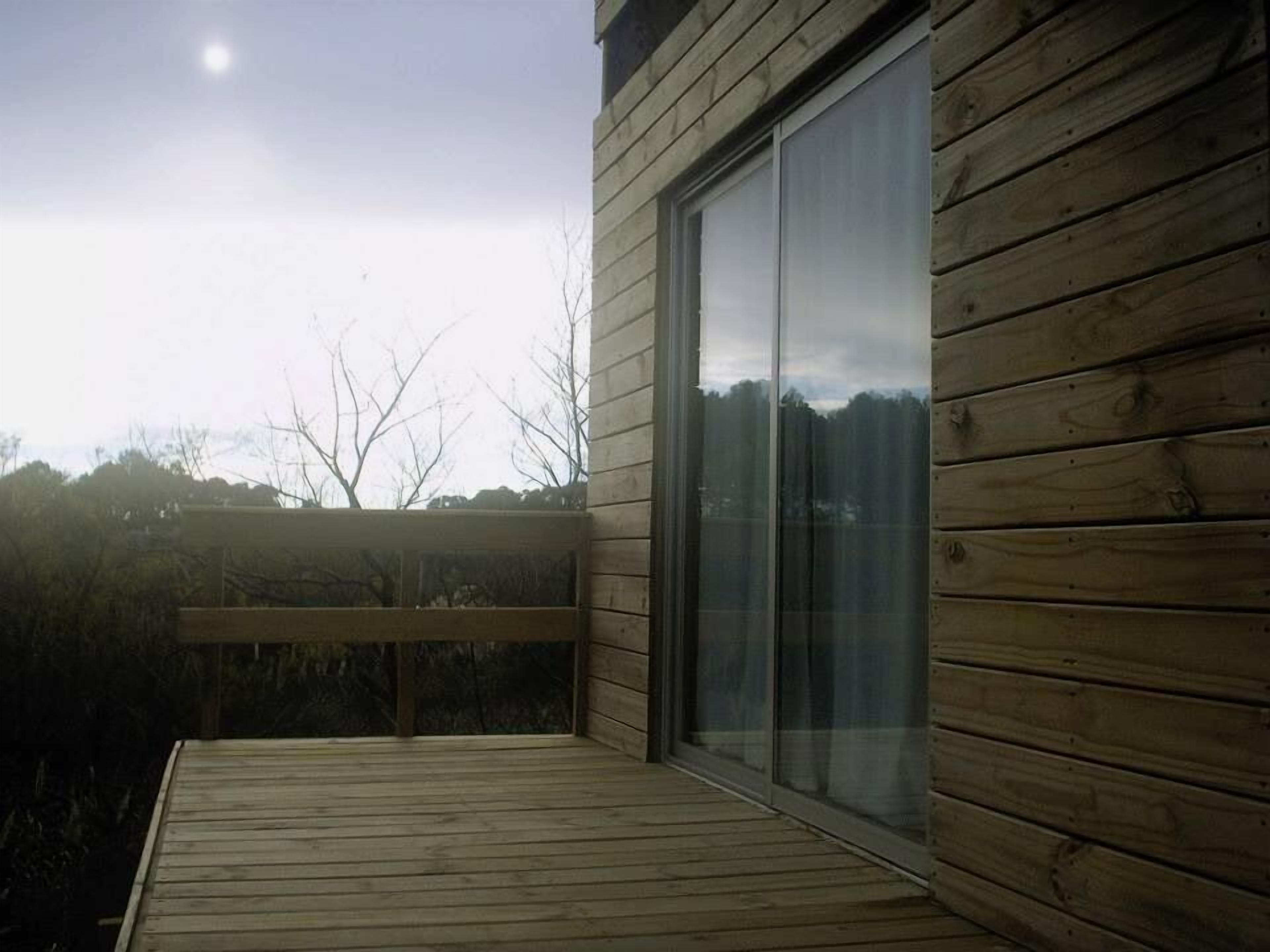 A wooden deck with a glass door leading to a room.