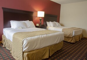 A hotel room with two beds, a nightstand, a lamp, and a patterned carpet.