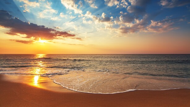 A beach with the sun setting over the ocean, creating a serene atmosphere. - Blue Dolphin Inn and Cottages (Grand Isle)