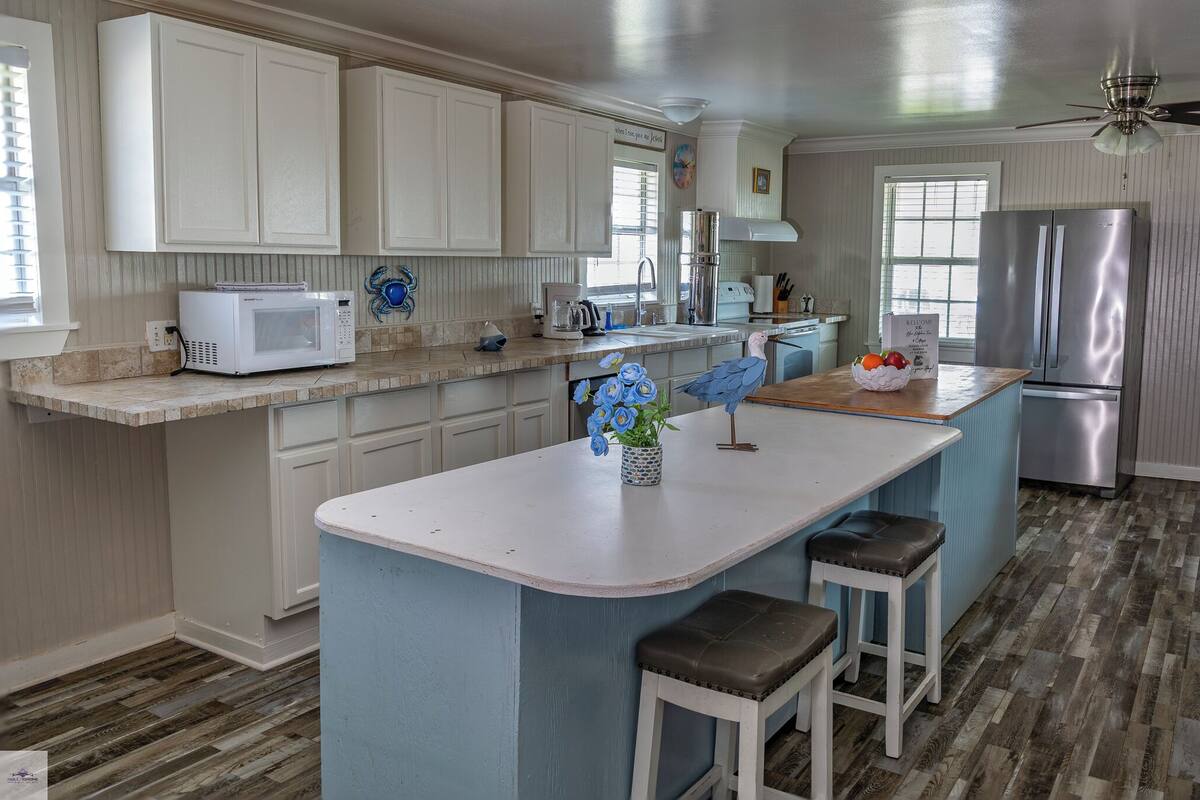 A kitchen with white cabinets, a stainless steel refrigerator, a microwave, and a coffee maker.