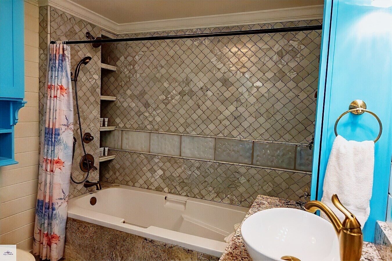 A bathroom with a shower, a bathtub, a sink with a gold faucet, and a towel ring.