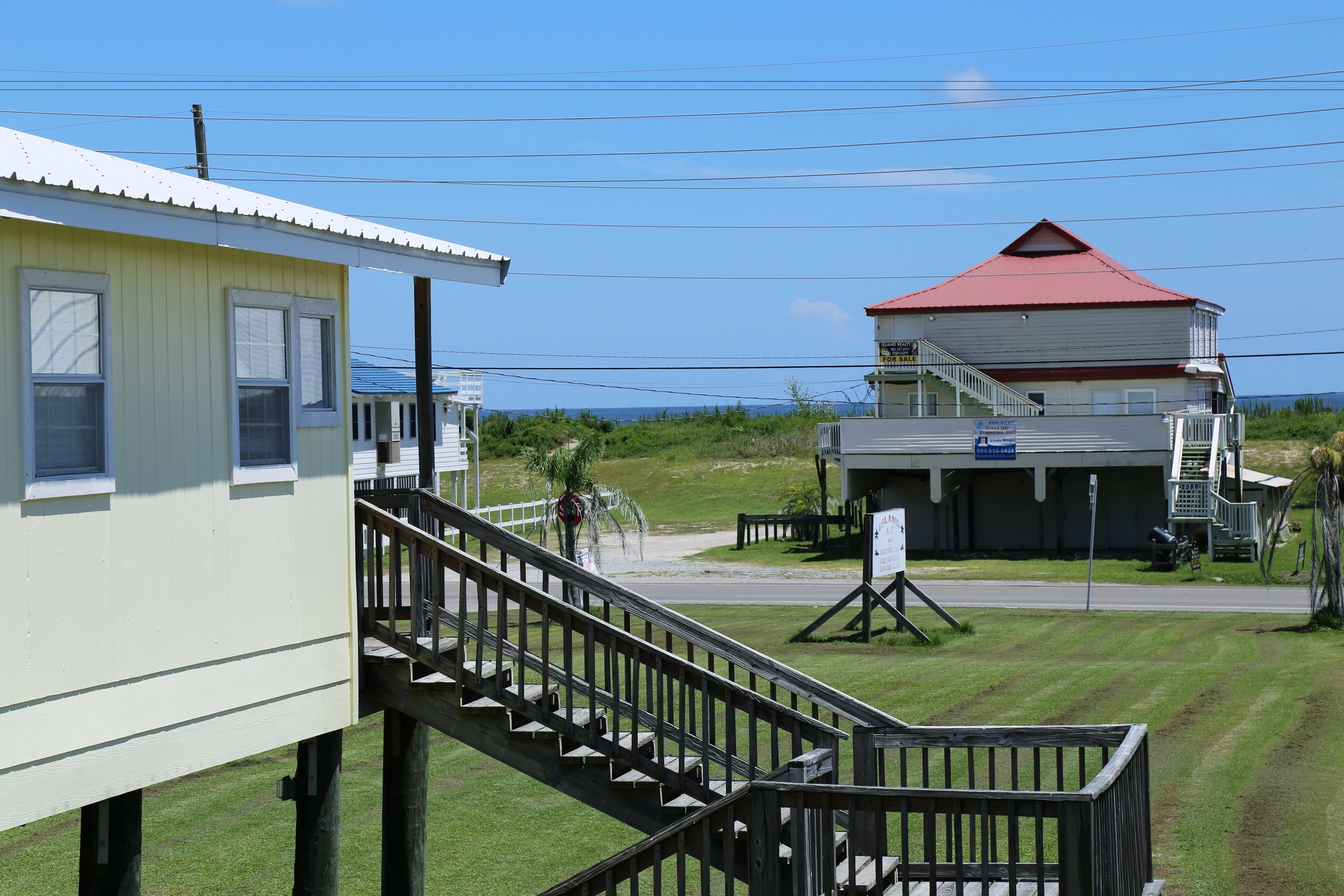 A building with a red roof, a staircase leading to a deck, and a signboard in front.