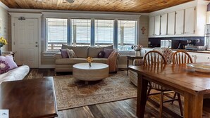 A cozy living room with a wooden ceiling, a sofa, a coffee table, and a dining area with chairs and a table. - Blue Dolphin Inn and Cottages (Grand Isle)
