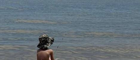 Eine Person sitzt auf einem Felsen am ruhigen Meer.