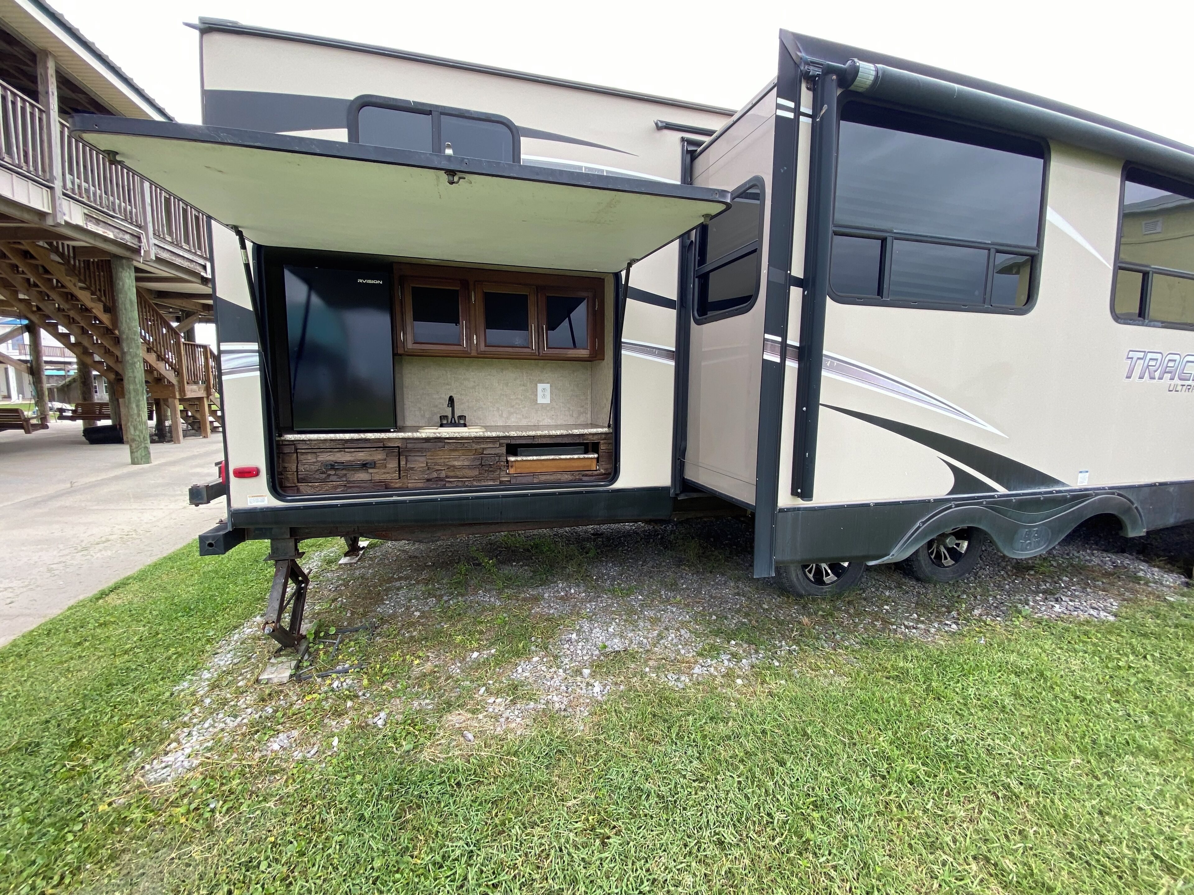A recreational vehicle with an open back, revealing a kitchen area with cabinets and a countertop.