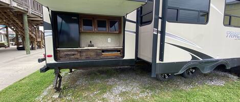 A recreational vehicle with an open back, revealing a kitchen area with cabinets and a countertop.