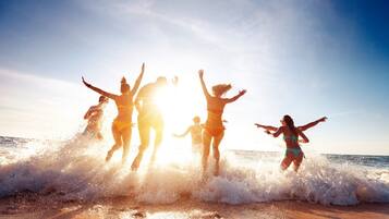 Escena de playa con gente saltando al agua.