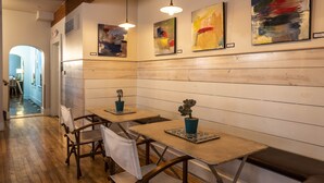 Un comedor con mesas y sillas de madera, obras de arte en las paredes e iluminación colgante.