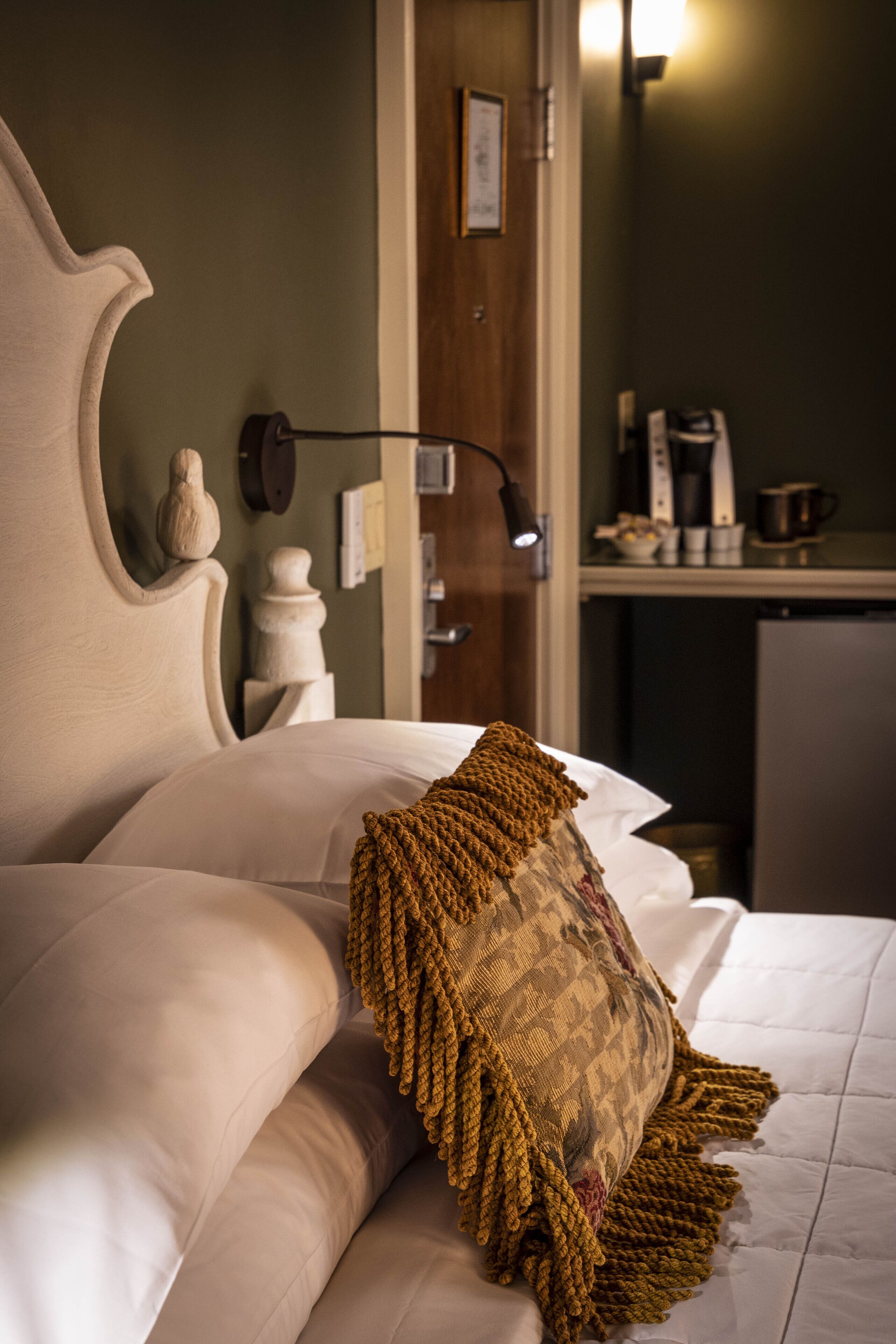 A neatly made bed with a patterned throw pillow and a headboard with a decorative finial.
