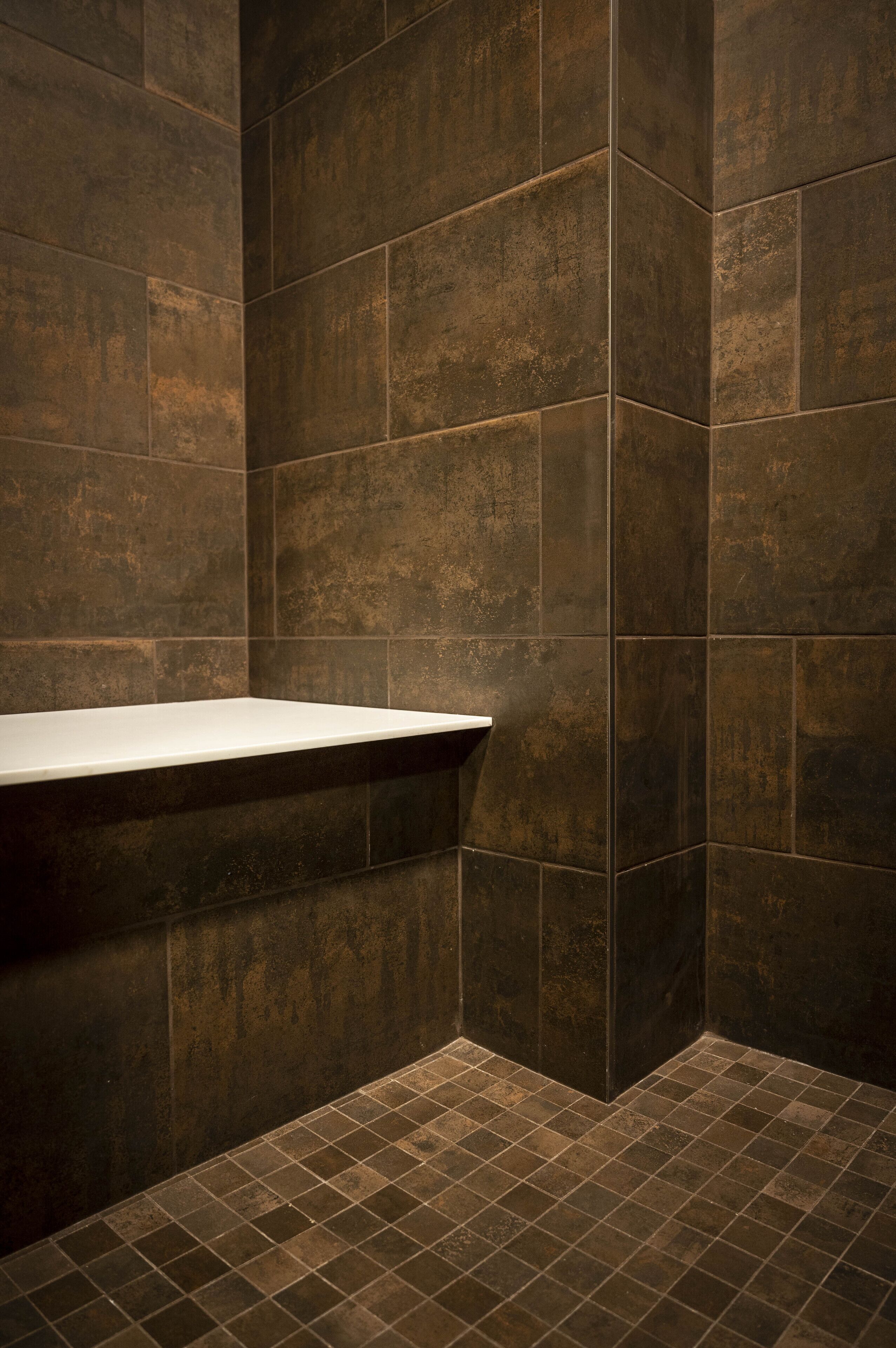 A bathroom with dark brown tiles, a white sink, and a tiled floor.