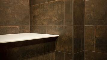 A bathroom with dark brown tiles, a white sink, and a tiled floor.
