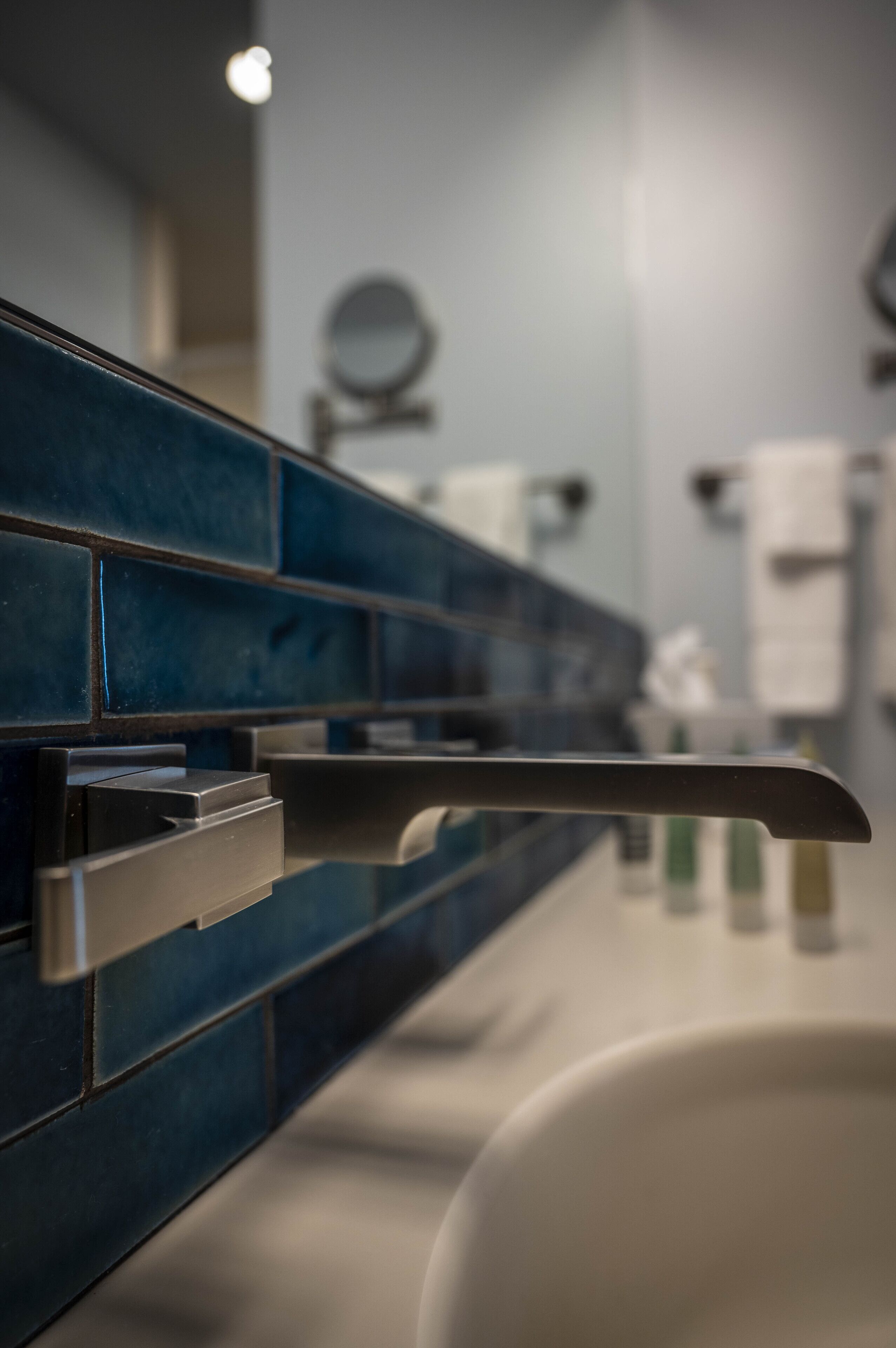 Un bagno con una parete piastrellata di blu, un lavandino bianco e uno specchio.