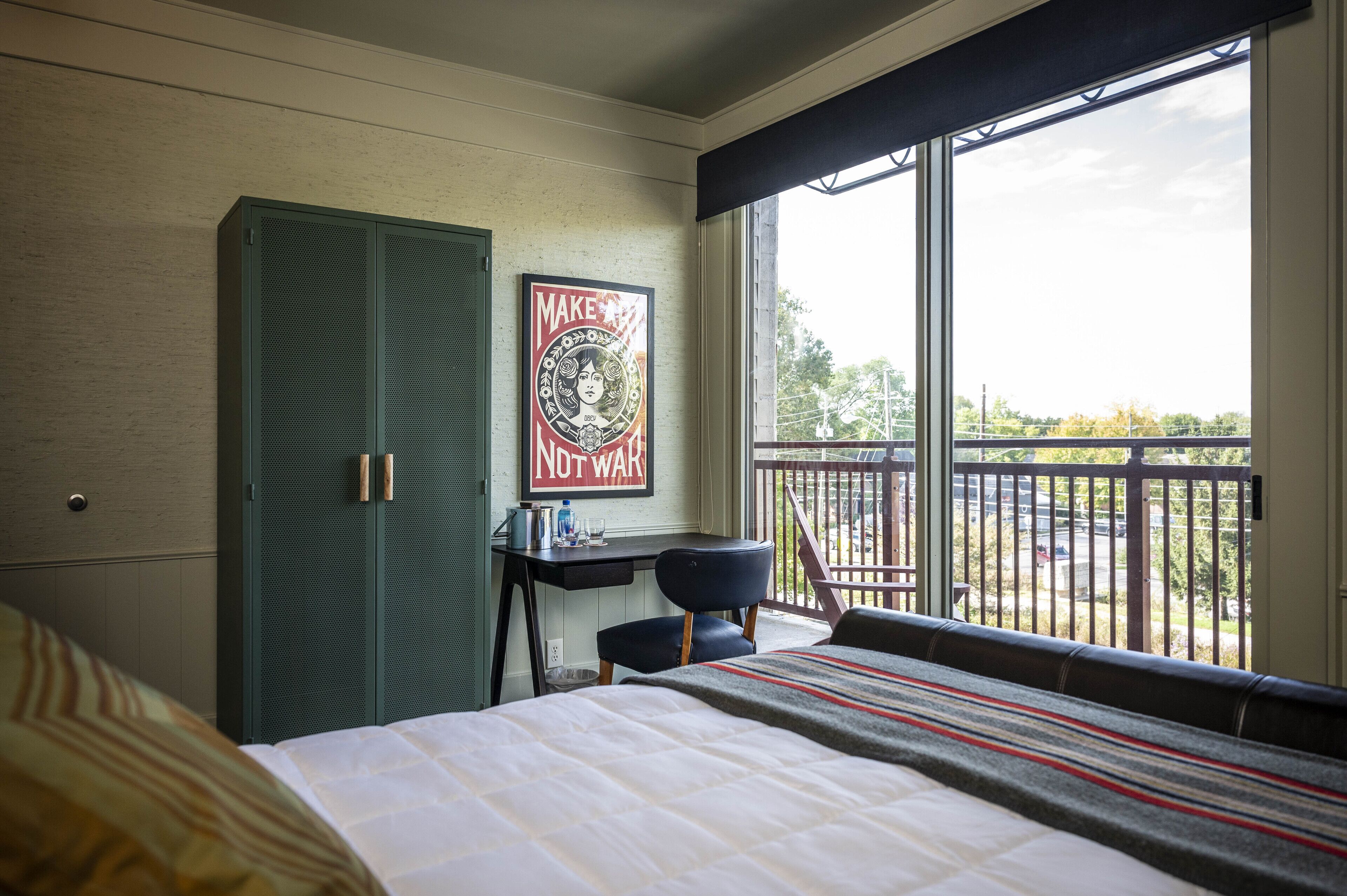 Une chambre d’hôtel comprenant un lit, un bureau, une chaise, une armoire et un balcon avec vue.