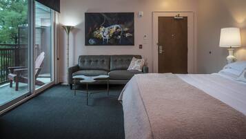 A hotel room with a large bed, a sofa, a coffee table, and a painting on the wall.