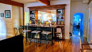 Zona de bar con taburetes de madera, una estantería y varias botellas.