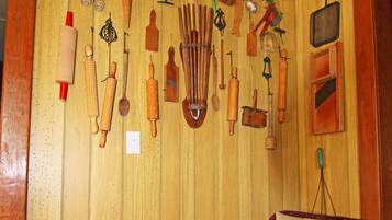 A room with wooden paneling, a wicker chair, and various kitchen utensils hanging on the wall.
