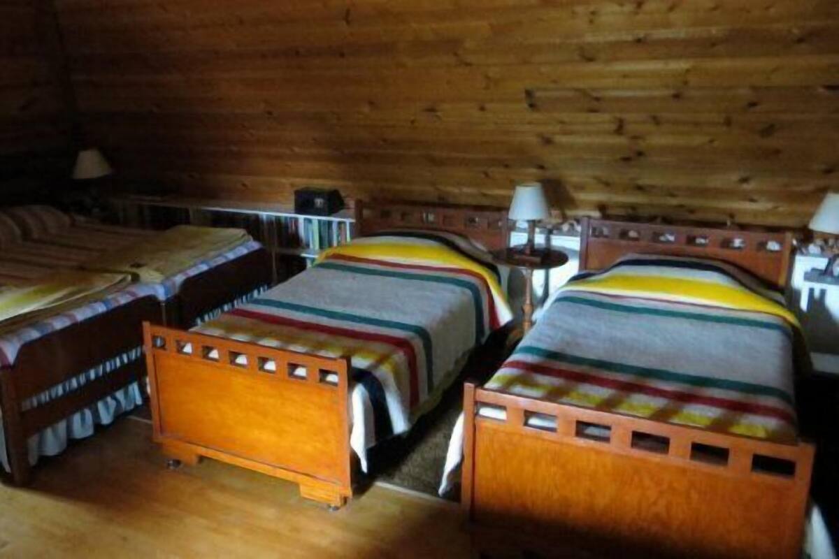 Eine Hütte mit drei Holzbunkebetten, jeweils mit einer gestreiften Decke.