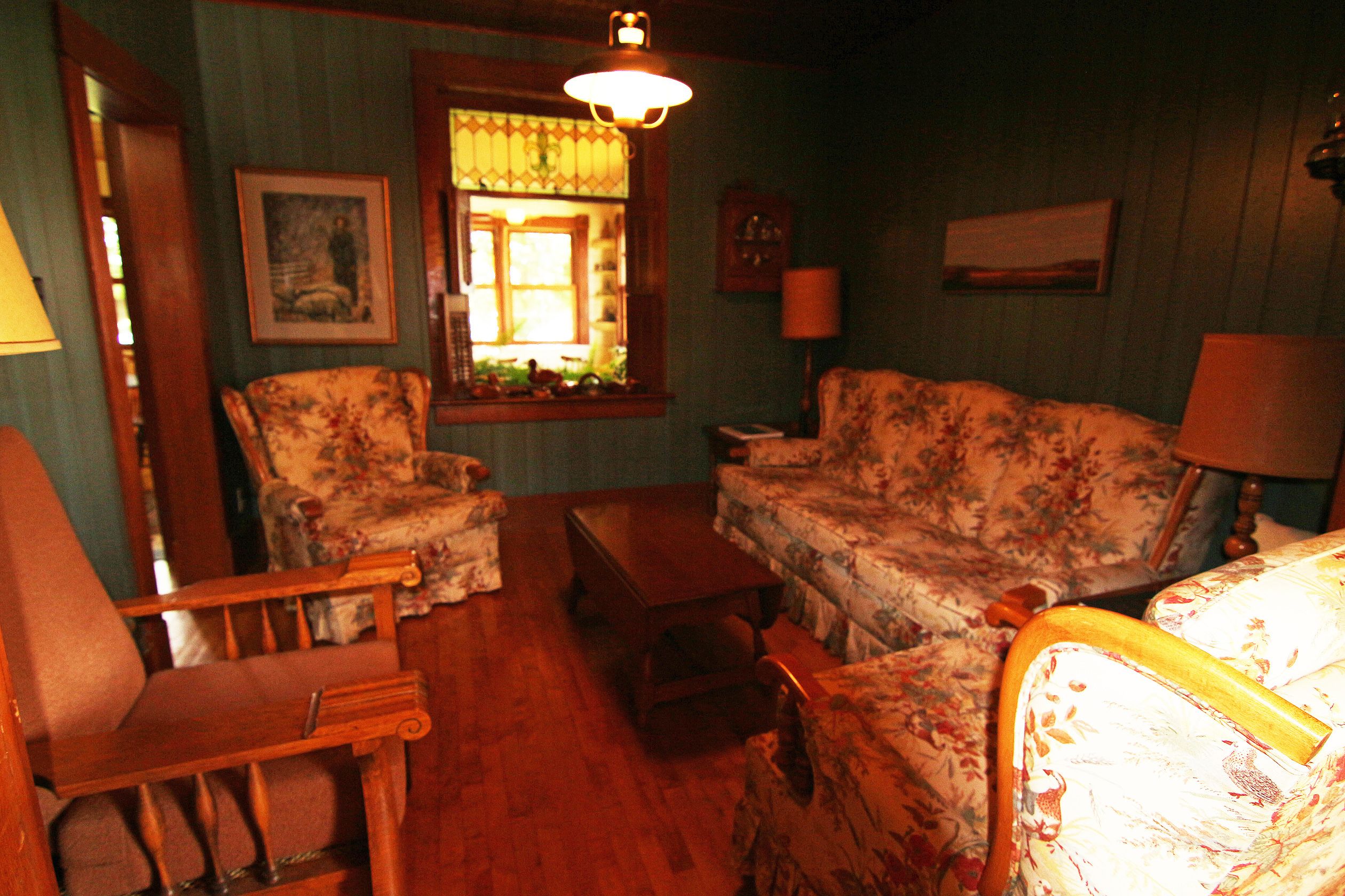 A cozy living room with floral-patterned furniture, a wooden coffee table, and a window with a view.