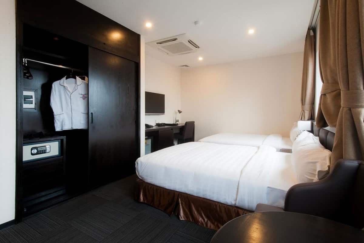 Ein Hotelzimmer mit Bett, Schreibtisch, Stuhl, Kleiderschrank und Safe.