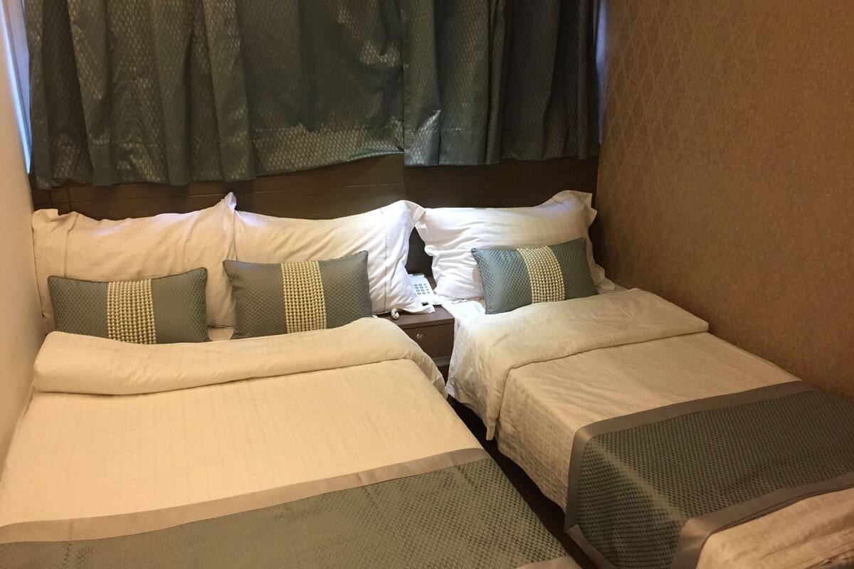 Ein Zimmer mit zwei Betten, jeweils mit weißer und grüner Bettdecke sowie passenden Kissen.