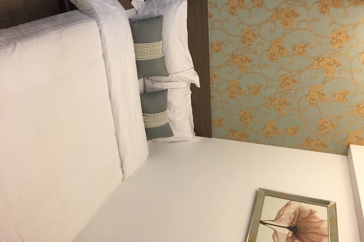 Ein Hotelzimmer mit einem Bett, einem Telefon und einer Wand mit floralem Muster.