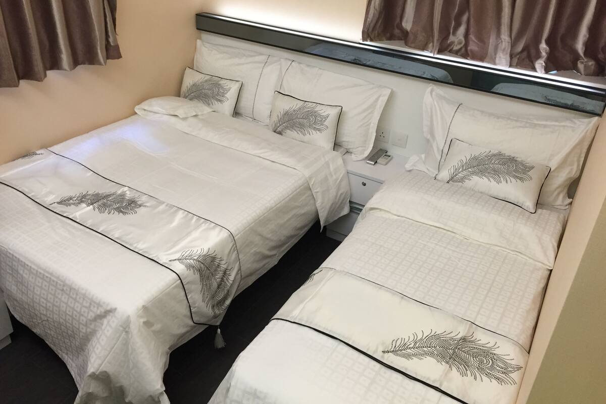 Ein Hotelzimmer mit zwei Betten, jeweils mit Kopfstütze und passenden Kissen.